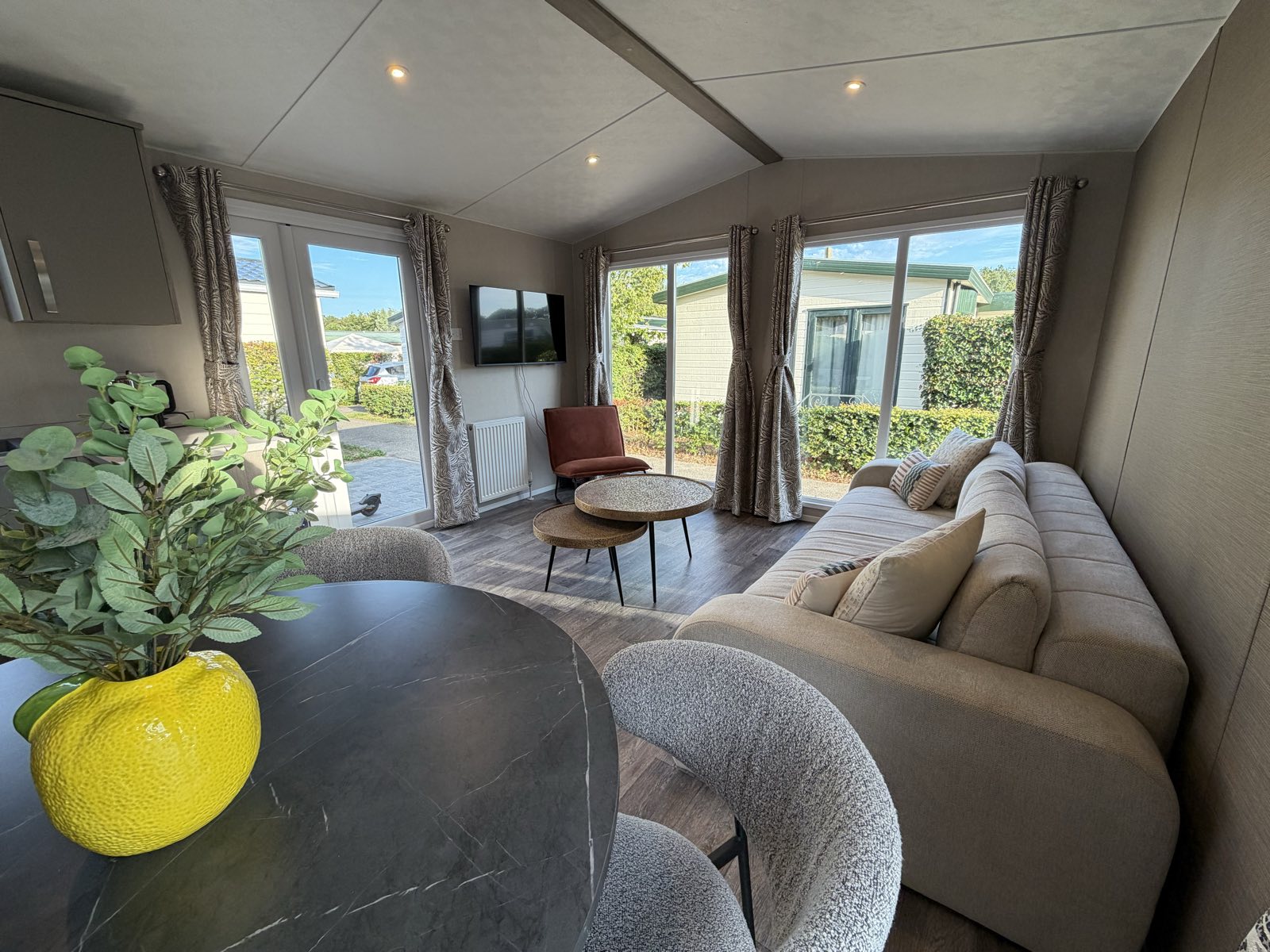 Woonkamer met ruime bank, smart tv en schuifdeuren naar het terras